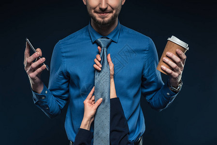女手握着商人的领带用电话和咖啡在蓝图片