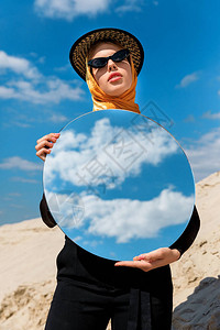 穿着圆镜的时尚装有魅力的女孩冒着圆镜子和阴图片