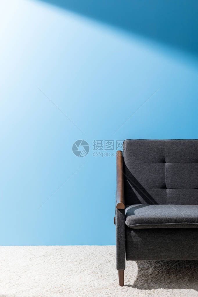蓝色墙壁前舒适的灰色沙发图片