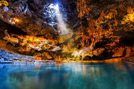 光线从地下洞穴的一个开口照射到洞穴和盆地历史遗址的温泉水中图片