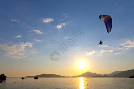 滑翔伞在日落时在海面上飞行图片