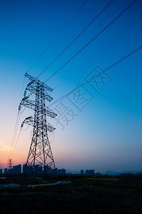 日出时蓝天中的钢制电力塔背景图片