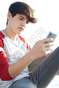 一个有吸引力和体贴的少年男孩放松和坐在海边的长椅上的肖像图片
