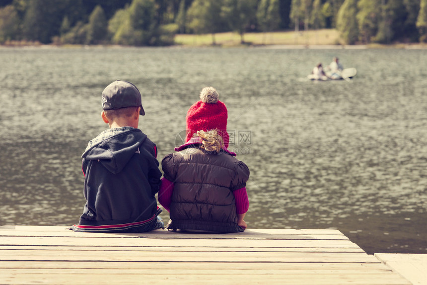 两名儿童坐在湖边浮水船图片