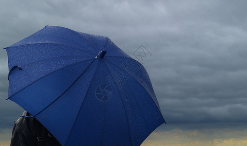 在一朵黑暗的风雨如磐的云彩的蓝色伞图片