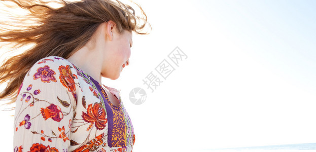 年轻的女孩在金色的沙滩上轻弹她的头发图片