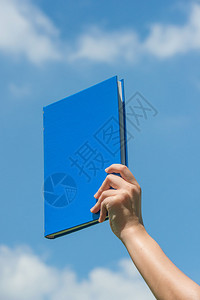 手拿着书在蓝天图片