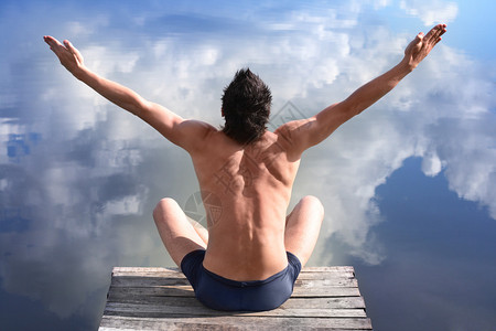 一个人手举着双手坐在水面上蓝色的天空图片