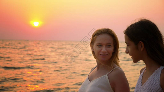身穿白衣的母亲和女儿赤脚在沙滩上走来去图片