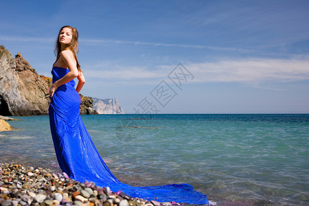 在海滩上穿着蓝色连衣裙的美丽女人图片