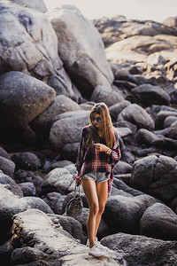 在日落时分在夏日海滩上穿着格子衬衫和衬衫的时尚髦女人在海滩的图片