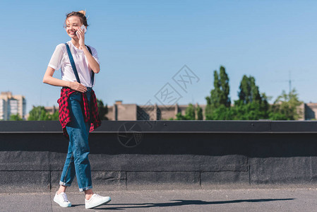 快乐的年轻女子在蓝天下在屋顶上用图片