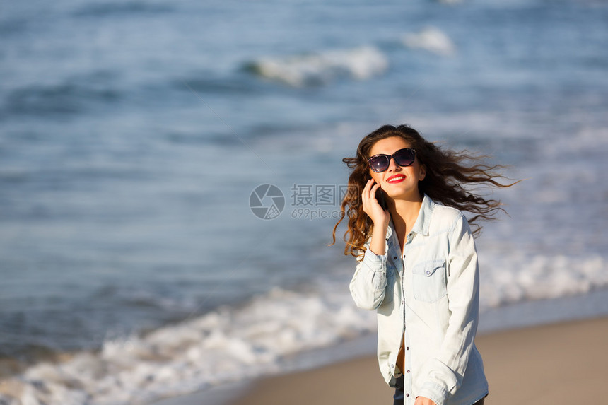 在沙滩上打电话的女人图片