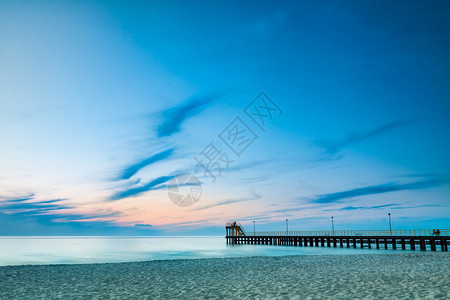 沿海岸线沙滩和日落时的码头图片