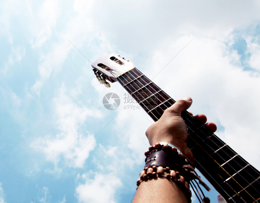 手在蓝天背景下弹吉他图片