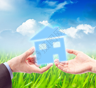 手掌中的房子对抗阳光明媚的蓝天作为房地产业务的象征图片