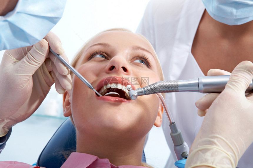 牙科医生和助理检查口腔时年轻女图像图片