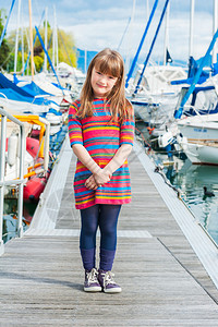 一个可爱小女孩在港口的户外肖像在阳光图片