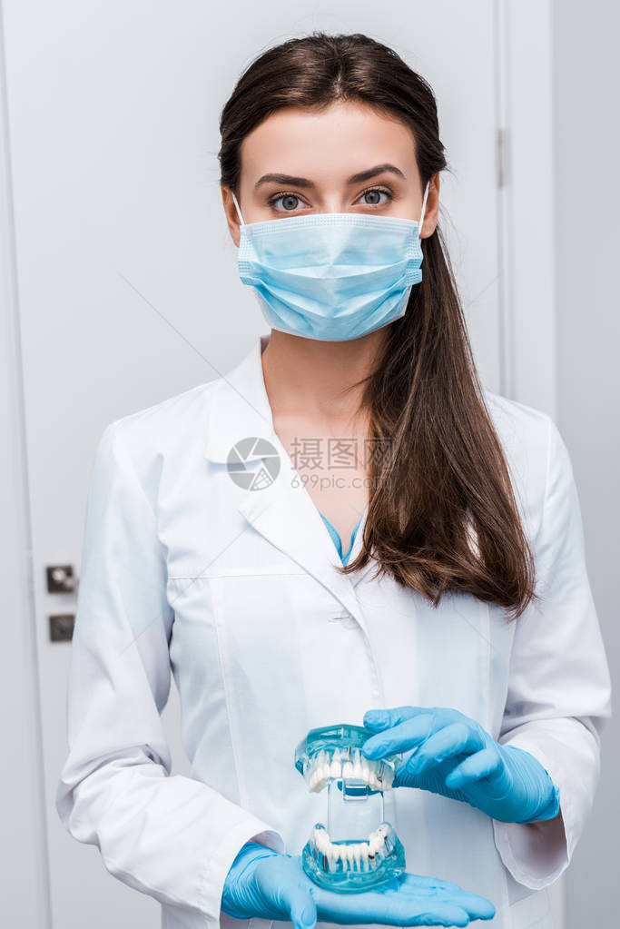 戴医用口罩的牙医和蓝色乳胶手套在诊所里图片