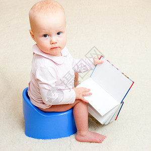 小女孩坐在蓝色便盆上打开书本图片