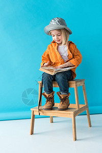 穿着牛仔裤和橙色衬衫的男孩坐在楼梯上阅图片