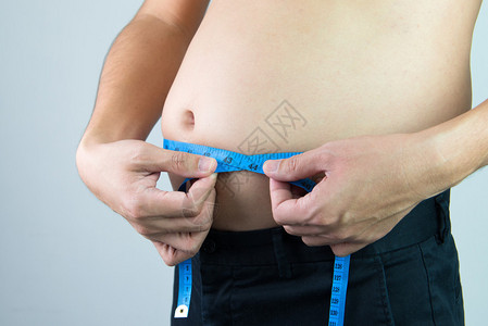 男人用卷尺测量他的腹部图片