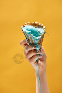 妇女将溶化的蓝冰淇淋放在黄色隔绝的咸图片