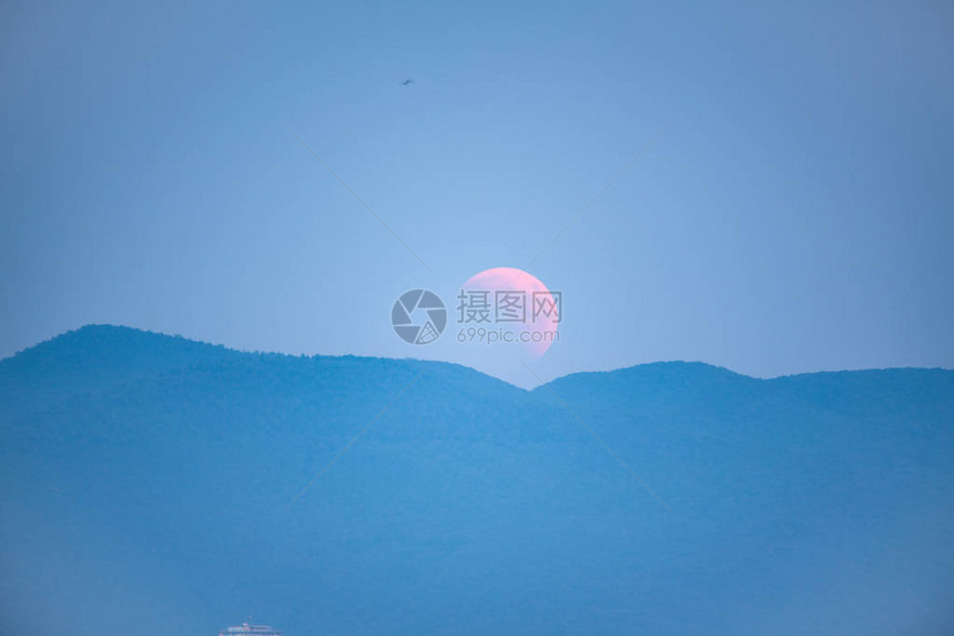 月食月亮升起在山后图片