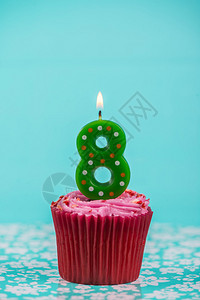 蓝色背景上带有八号蜡烛的生日杯蛋糕图片