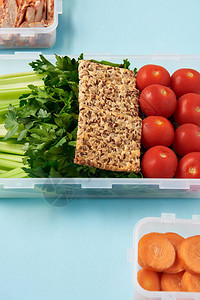 近距离观察装满健康蔬菜肉片和蓝底饼干的食品集装箱安排情况一图片