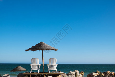 海滩上有两把椅子和伞子葡萄牙阿图片