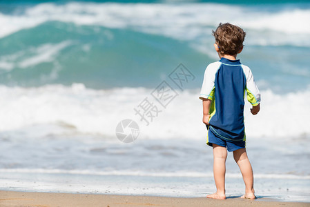 小男孩看着海边的巨浪图片