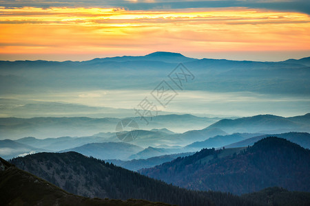 美丽的橙色夕阳下的蓝色山脉和丘陵图片