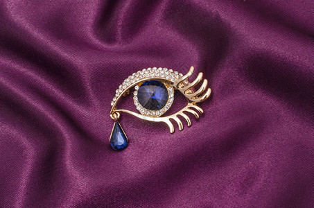 丝质织物上镶有钻石和大蓝宝石的金胸针眼睛图片