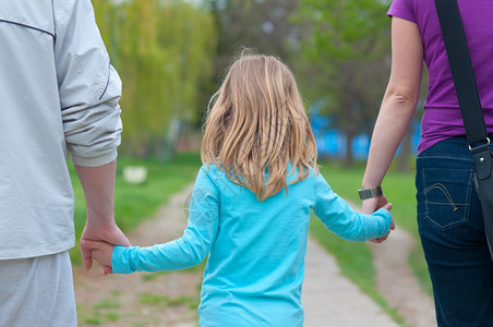 小女孩在公园散步时握着父母的手图片