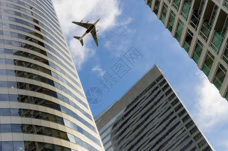 飞机在玻璃办公楼上空飞图片