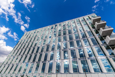 玻璃反射办公大楼以云彩和阳光照耀的蓝色图片