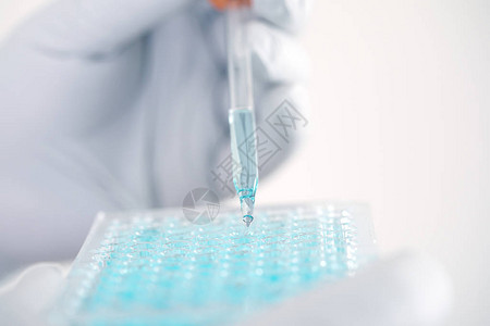 关闭一位在实验室工作的科学家分析微管板中DNA分子的蓝色提取物临床或科学背景图片
