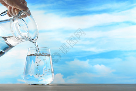 新鲜清洁的饮用水从壶中倒入玻璃图片