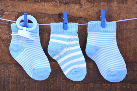 一只蓝宝袜子和假奶嘴挂在绳子上与生锈的黑图片