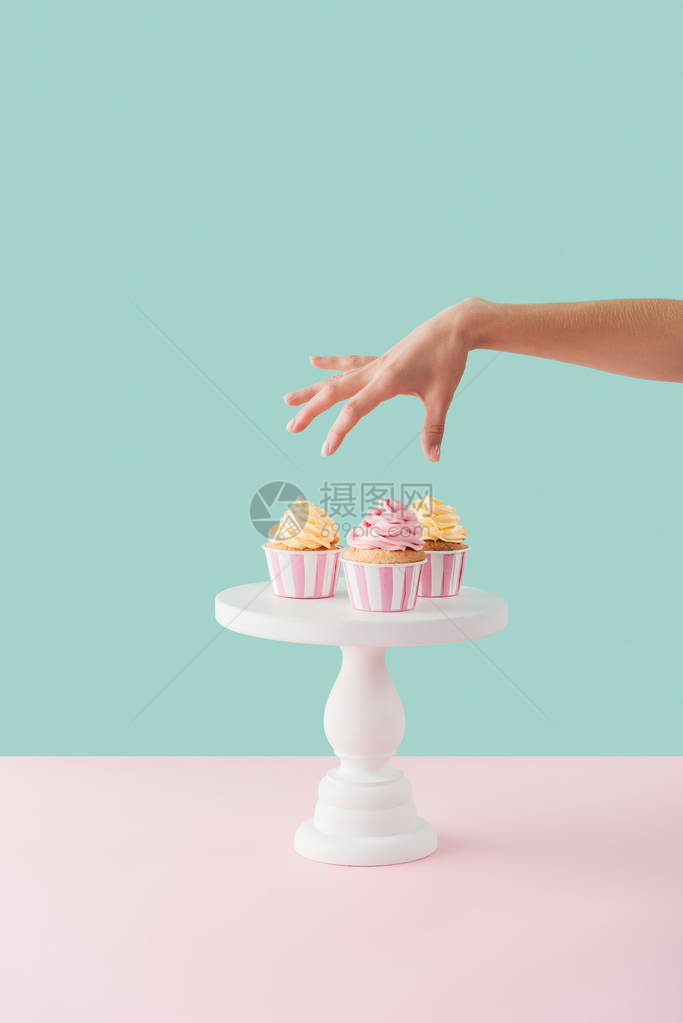 女人从蛋糕架上拿纸杯蛋糕的剪影图片