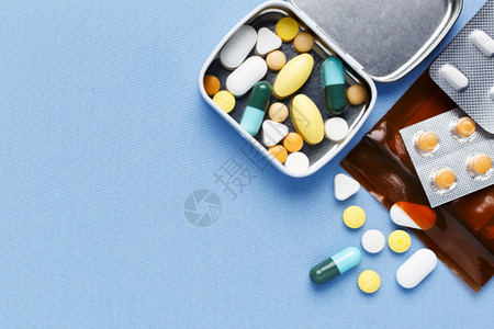蓝色织物背景中的盒装药丸和药袋图片