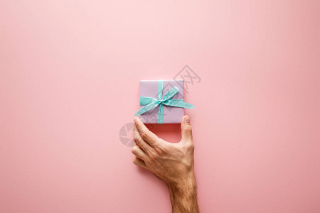 持有紫色小礼物盒和粉红背景的蓝色带子的背景图片