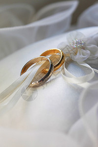 白色缎面织物上的结婚戒指图片