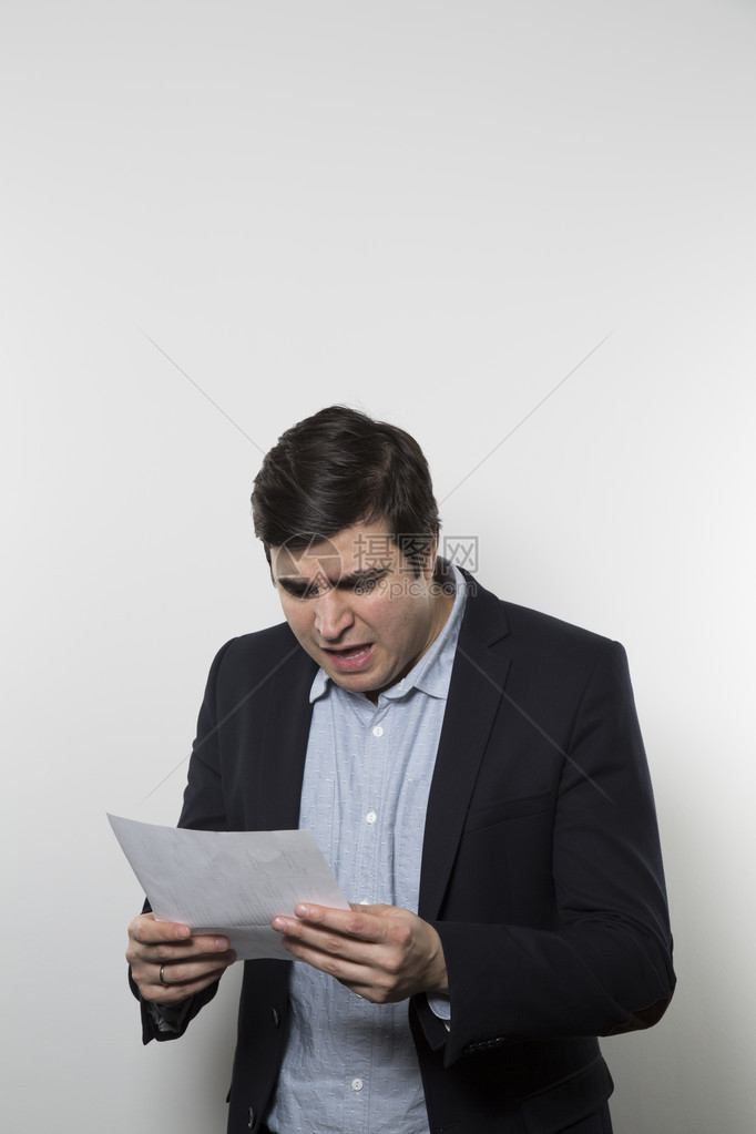 深色黑头发的欧洲商人用葡萄树眼神盯着一张纸在梯度背景面前图片