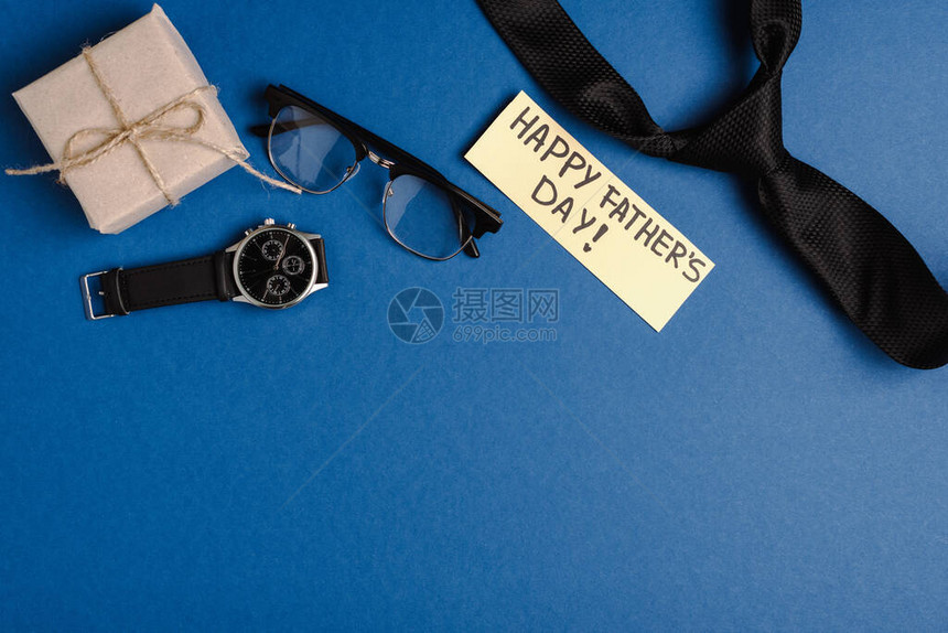 礼物盒的顶端视图带快乐父亲日信函的贺卡和蓝底黑领带手表图片