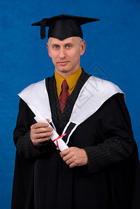 身着黑色毕业礼服的年轻男子持有蓝色背景的学位证书图片