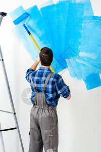 用蓝色油漆刷墙的人后视图图片