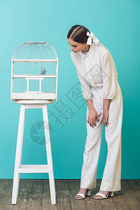 穿着白衣服的漂亮女孩在笼子里看鹦鹉图片