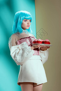 穿着蓝假发的时装女孩拿着蛋糕在图片